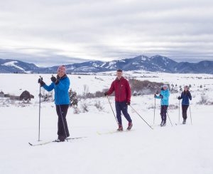 Mike McCormick cross country skiing outdoors in Bozeman, MT with his wife, two daughters, and two dogs